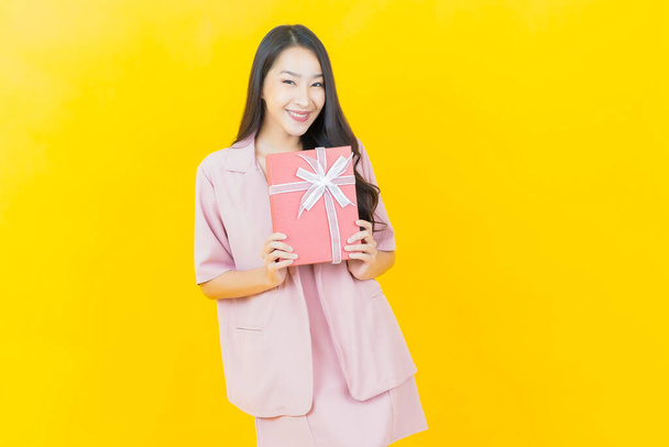 Portrait beautiful young asian woman smile with red gift box on color background - Fotó, kép