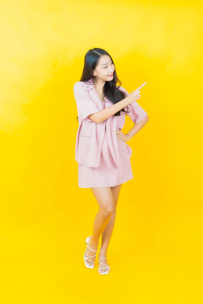 Retrato hermosa joven asiática mujer sonrisa con acción en color fondo - Foto, Imagen