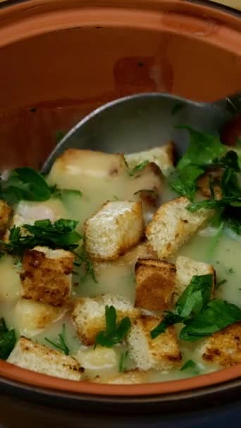 Pea cream soup is mixed with metal spoon with chopped herbs and fried croutons. Healthy vegetarian food concept. - Footage, Video