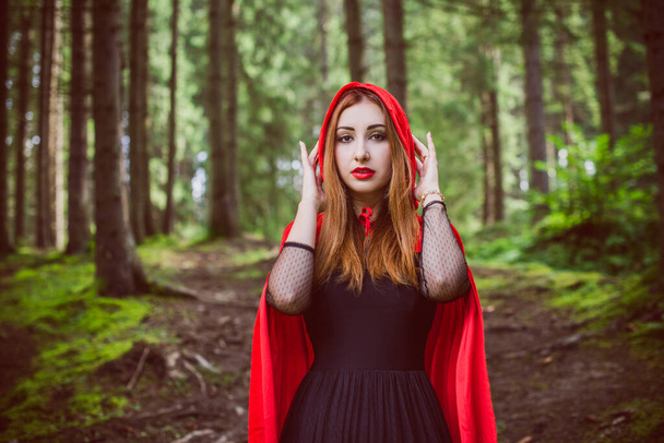 Concept of Halloween. Beautiful and simple costume of little red hood. Mysterious hooded figure in misty forest. Girl in red raincoat. Cosplay Fairy Tale Little Red Riding Hood - Фото, изображение