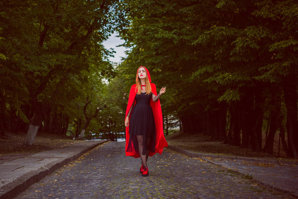 Concept of Halloween. Beautiful and simple costume of little red hood. Mysterious hooded figure in misty forest. Girl in red raincoat. Cosplay Fairy Tale Little Red Riding Hood - Photo, Image