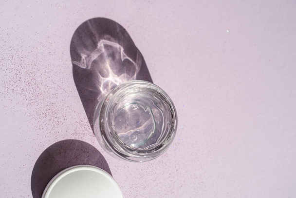 Transparent gel in a jar on a lilac background. - Photo, Image
