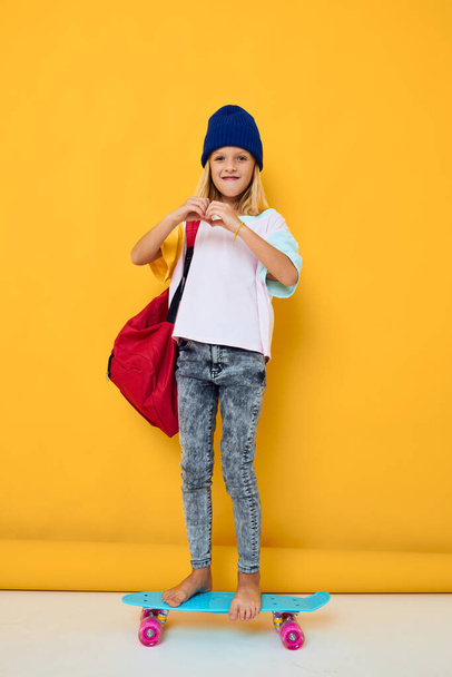 Foto von niedlichen kleinen Mädchen mit einem Skateboard auf dem Kopf gelben Hintergrund - Foto, Bild