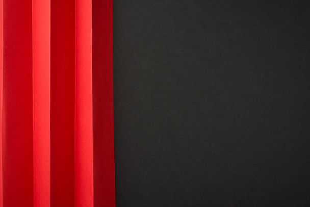Top view photo of red paper sheet with vertical folds on isolated black background with empty space on the right - Photo, Image