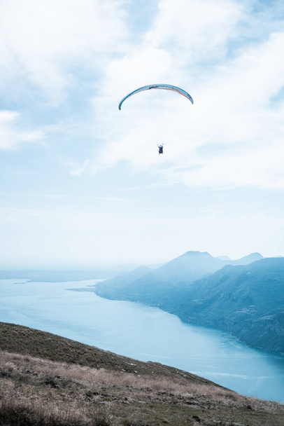 GARDA, ITALY - Aug 27, 2021: A parachute flyi over the Garda lake in North Italy - Photo, Image