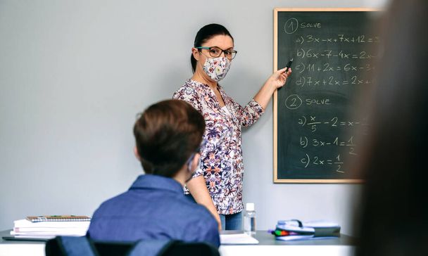 Teacher with mask in math class with student raising hand - Foto, Imagem