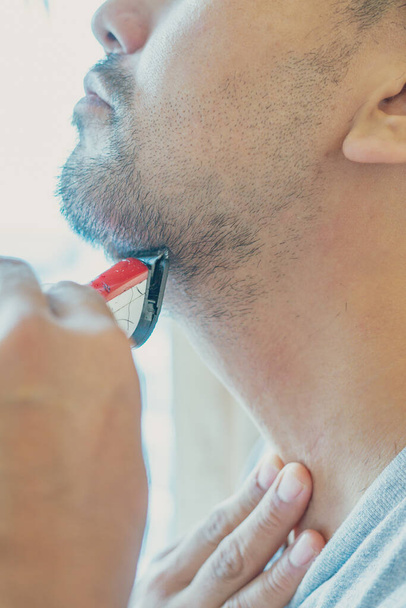 Shaving beard with electric razor machine. - Фото, изображение