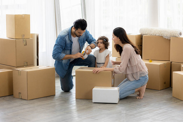 The family just bought new furniture and helped organize the house. Mon dad and daughter just moving new home. They unpacking parcel box and arranging on the floor in the living room. - Photo, Image