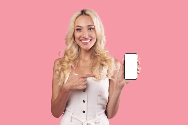 Kobieta trzyma i wskazuje biały pusty ekran smartfona - Zdjęcie, obraz