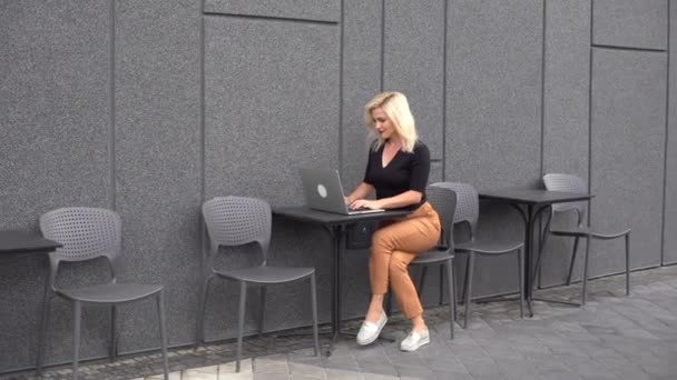 Jonge zakenvrouw werkt achter de computer in café. Jong meisje downshifter werken op een laptop, werkdag. - Video