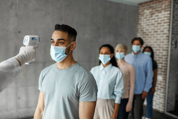 Multiracial men and women in face masks checking body temperature - Photo, Image