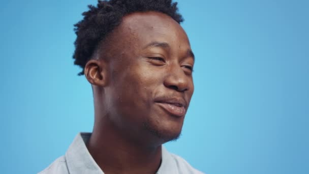 Interjú koncepció. Közelkép portré fiatal pozitív afro-amerikai srác beszél beszélgetőpartner, kék háttér - Felvétel, videó