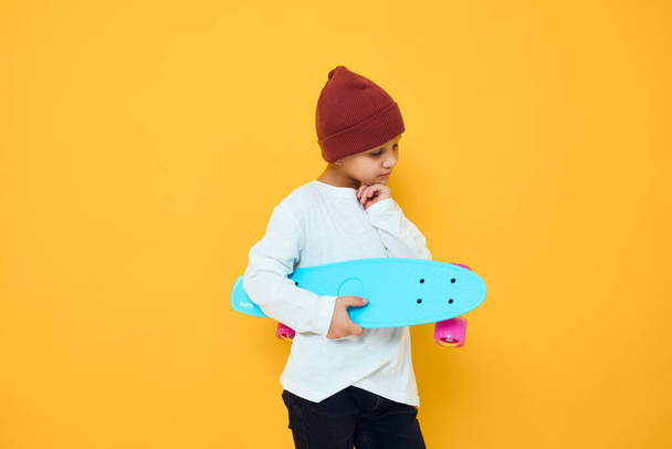 Cool sorrindo menino em um skate chapéu vermelho em suas mãos estúdio posando - Foto, Imagem