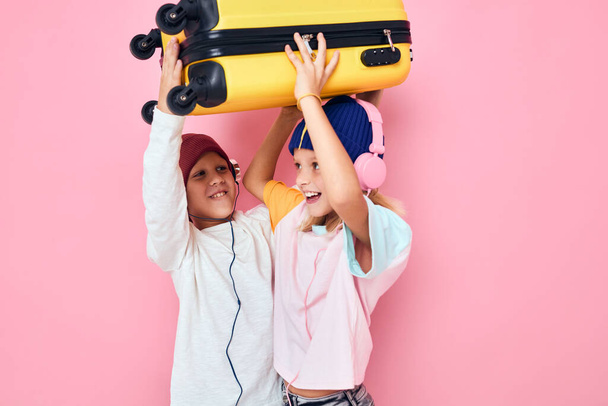 aranyos mosolygós gyerekek egy sárga bőrönddel a kezében stúdió pózol - Fotó, kép
