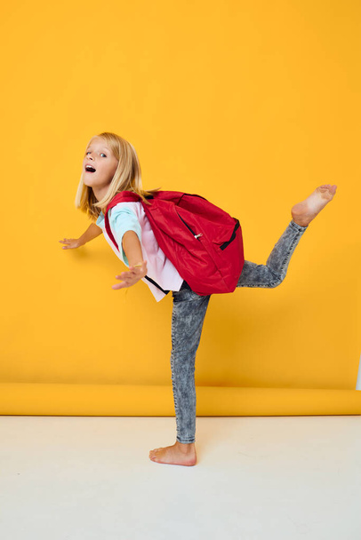 šťastný školačka stylové oblečení červená batoh žlutá barva pozadí - Fotografie, Obrázek