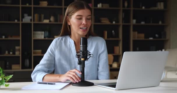 Young woman sit before laptop talk to microphone record podcast - Metraje, vídeo