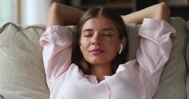 Female teenager wear headphones rest on sofa learn easy english - Πλάνα, βίντεο