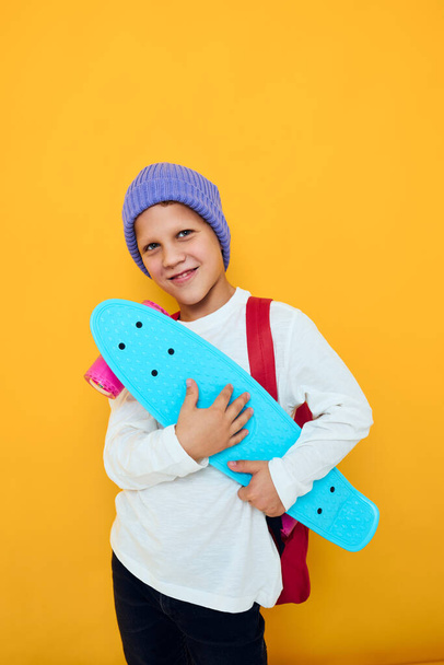 happy schoolboy with red backpack blue skateboard studio lifestyle - Φωτογραφία, εικόνα