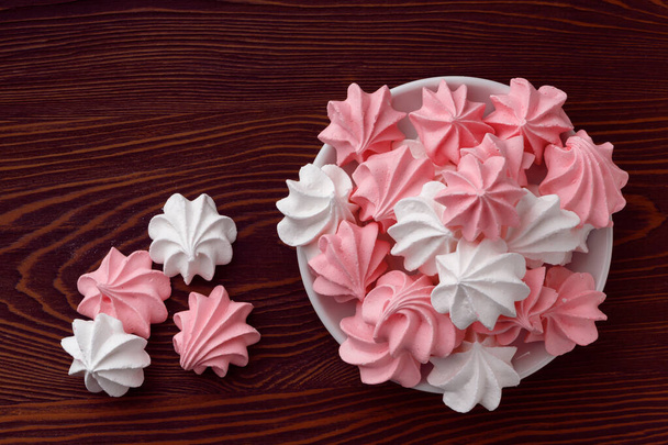 Pink and white meringues on a dark wooden table .Top view - Zdjęcie, obraz