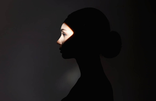 beautiful girl in the dark. young woman with shadow on the face - 写真・画像