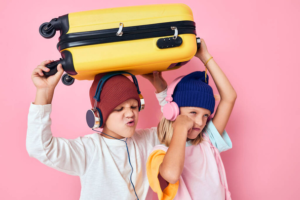 радісний хлопчик і дівчина стильний одяг валіза навушники студія позує
 - Фото, зображення