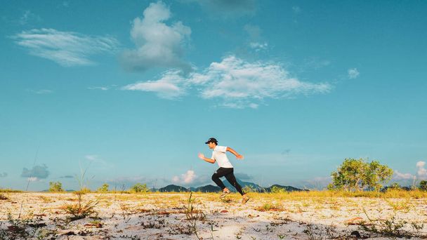 Aasialainen mies kävelee hiekassa kauniina päivänä. Liikunnan ja rentoutumisen käsitteet - Valokuva, kuva