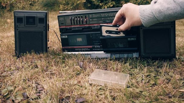 Człowiek bierze kasetę magnetofonową z futerału wkłada ją do starego magnetofonu retro - Zdjęcie, obraz