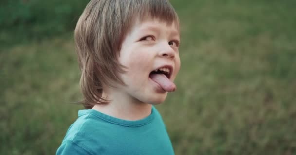 小さく可愛い女の子の子供は舌を見せて顔を作る。近くに肖像画 - 映像、動画