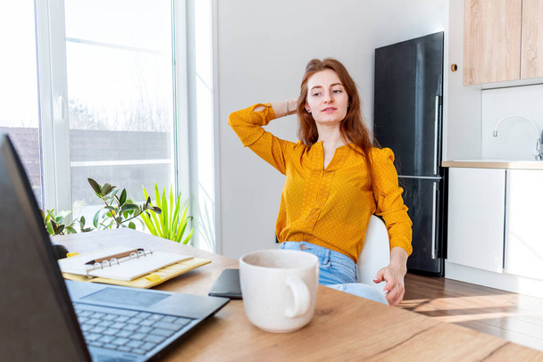 Young business woman is resting with a cup of cocoa after work Internet using a computer. Girl has a slow lifestyle near a laptop. Concept a comfort zone in house. - 写真・画像