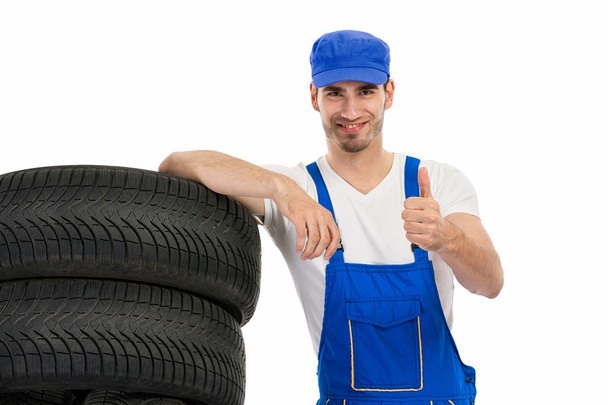 mechanic with tyre giving a thumbs up  - Foto, afbeelding