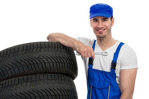 Motor mechanic changes a tyre - Foto, afbeelding