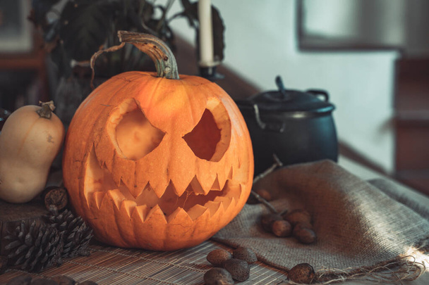 Halloween spooky pumpkin face in a table with decoration. Skeleton, candles, nuts. Teal and orange beautiful still life. - 写真・画像