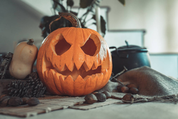 Halloween spooky pumpkin face in a table with decoration. Skeleton, candles, nuts. Teal and orange beautiful still life. - 写真・画像