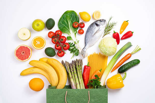 Terveellistä ruokataustaa. Terveellistä ruokaa paperipussissa kalaa, vihanneksia ja hedelmiä valkoisella. Ruokakaupan konsepti. Terveellinen syöminen, suunnittelu ateria, elintarvikkeiden osto - Valokuva, kuva