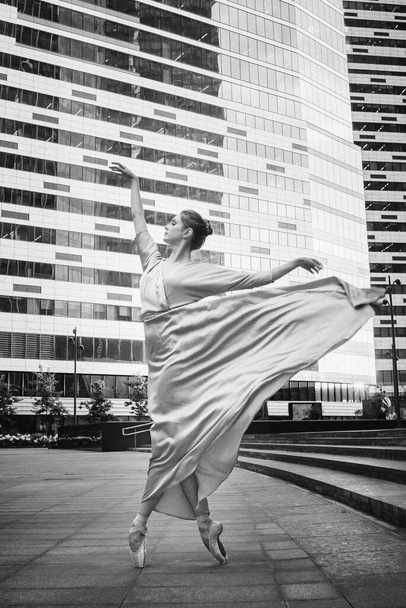 Μπαλαρίνα, χορεύτρια μπαλέτου σε μοντέρνο φόντο της πόλης. Κοκκινιστή ασπρόμαυρη κοκκώδης φωτογραφία. - Φωτογραφία, εικόνα