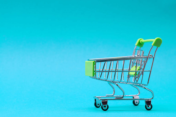 Shopping trolley on a blue background. Green color. Place for an inscription. Shopping concept. - Zdjęcie, obraz