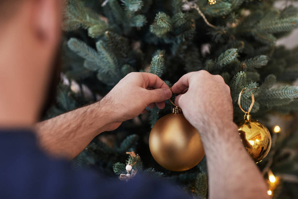 Kerstbal aan boom hangen - Foto, afbeelding