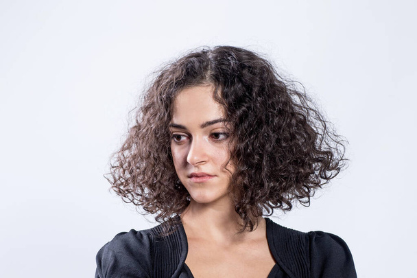 Portrait of beautiful girl with curly hair. Stylish haircut, hairstyle, styling. Caucasian young woman sadly looks to the side, big brown eyes, brunette. Concept of individuality, mood swings, sadness - Φωτογραφία, εικόνα
