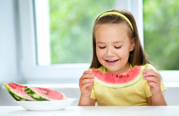 Cute little girl is eating watermelon - Foto, afbeelding