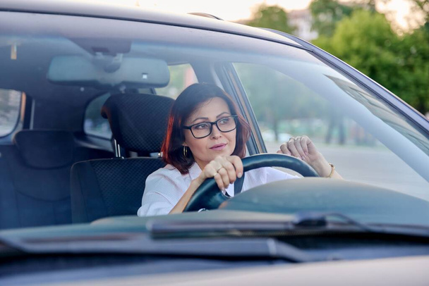 Middle-aged woman driver with glasses, female driving a car. - Fotó, kép