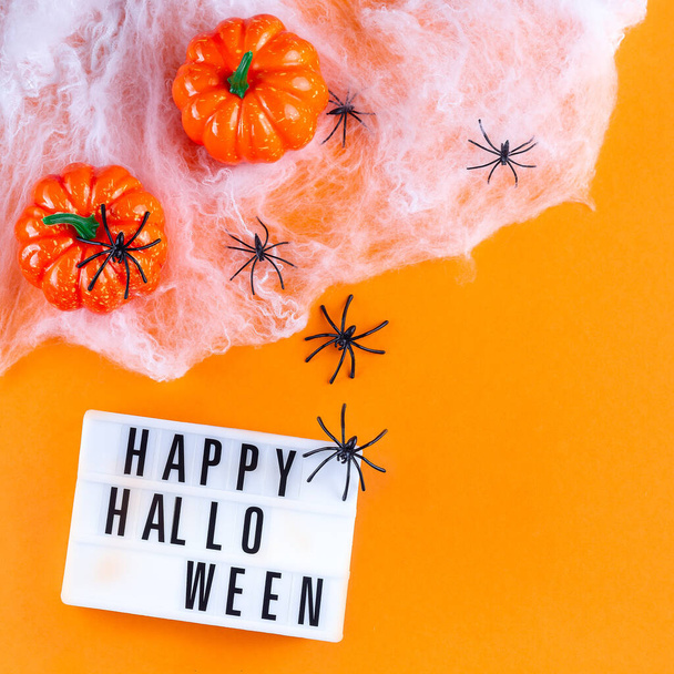 Halloween background with web, spiders and pumpkin, on orange paper, square format, top view, copy space - 写真・画像