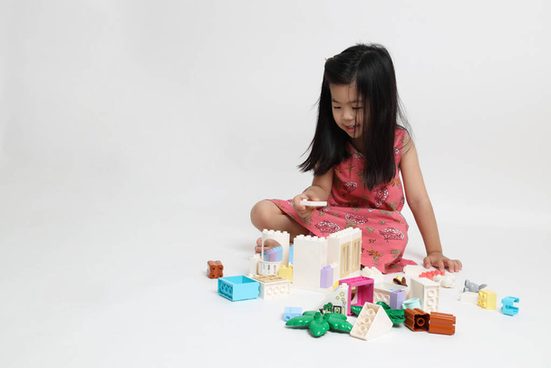 La ragazza asiatica gioca giocattolo sullo sfondo bianco. - Foto, immagini