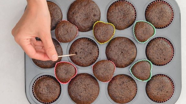 Suklaa cupcakes lähellä paistinpannulla. Kokki tarkistaa kuppikakkuja Doneness käyttämällä hammastikku testi - Valokuva, kuva