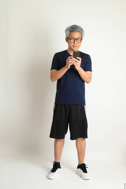O homem sênior asiático com roupas esportivas no fundo branco. - Foto, Imagem