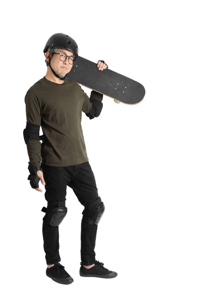 The Asian man with protective gear and skateboard standing on the white background. - Photo, Image