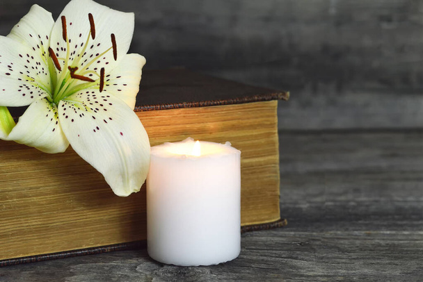 White candle, lily flower and closed book. Condolence card with copy space - Valokuva, kuva