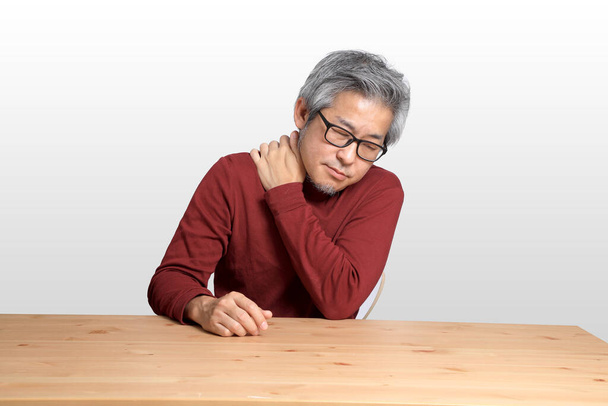 The Senior Asian man sitting at the desk on the white background. - Zdjęcie, obraz