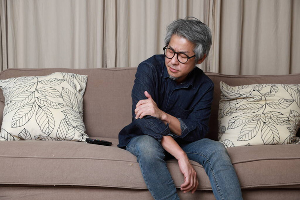 El hombre asiático mayor sentado en el sofá en el salón. - Foto, Imagen