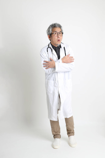 The senior Asian physician on the white background. - Foto, afbeelding