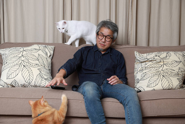 The senior Asian man sitting on the sofa in the livingroom. - Photo, image
